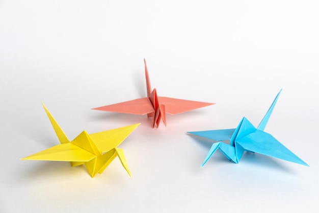 Grullas de origami japonesas tradicionales hechas de papel sobre un fondo blanco Pájaros de papel multicolor La creatividad de los niños Un símbolo de paz