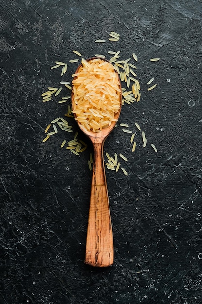 Foto grumos de arroz em uma colher de pau em um fundo de pedra comida saudável