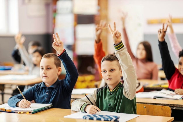 Grundschüler heben die Hände in der Klasse