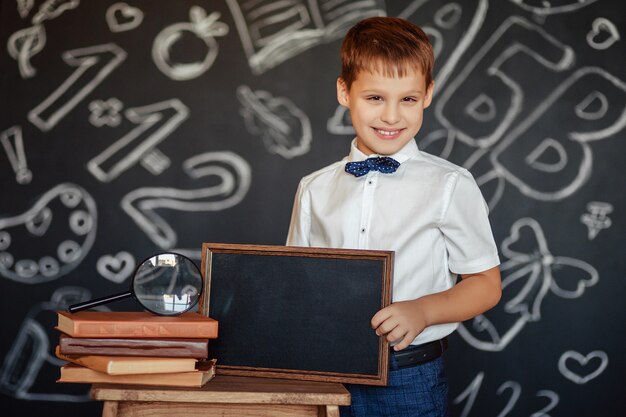 Grundschüler Junge mit einer schwarzen Tafel in seinen Händen