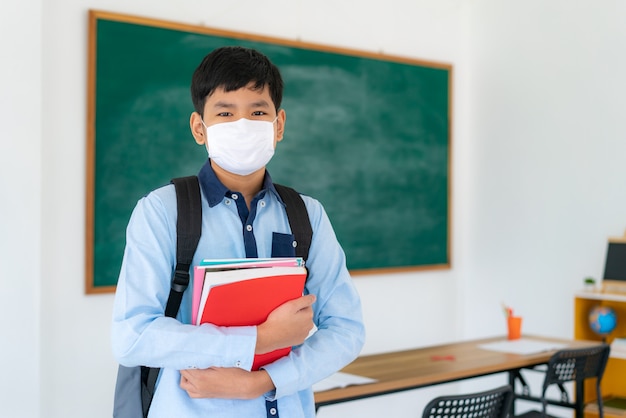 Grundschüler Junge mit Rucksack und Büchern mit Masken