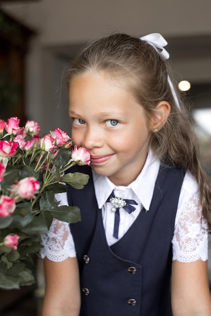 Grundschülerin in Schuluniform mit Rosen