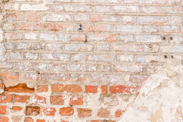 Grunge-Hintergrund. Alte rote Backsteinmauer mit heller, verlassener Putzstruktur