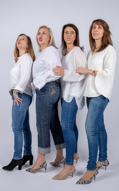 Grupo de 4 mujeres, amigas, de mediana edad divirtiéndose en una sesión de fotos.