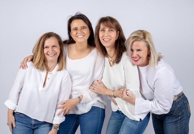 Foto grupo de 4 mujeres, amigas, de mediana edad divirtiéndose en una sesión de fotos.