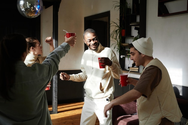 Grupo de adolescente feliz divirtiéndose en una fiesta bebiendo bebidas alcohólicas y bailando