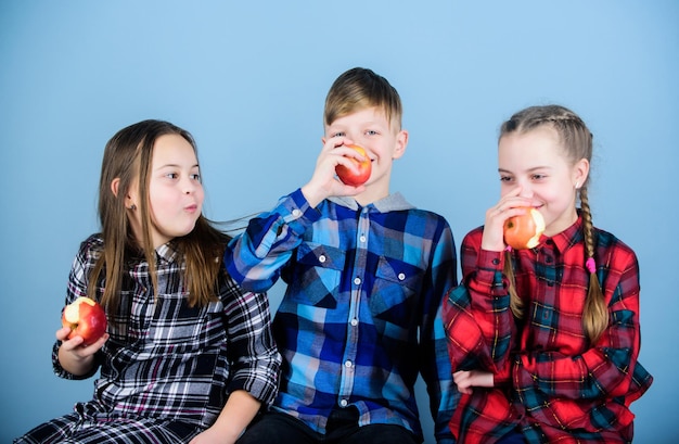 Grupo de adolescentes alegres divirtiéndose y comiendo manzanas Adolescentes con merienda saludable Dieta saludable y nutrición vitamínica Niños y niñas amigos comen merienda de manzana mientras se relajan Concepto de merienda escolar