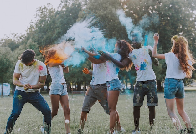 Grupo de adolescentes jugando con colores en el festival holi, en un parque