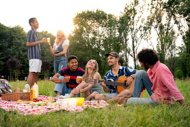 Grupo de adolescentes multiétnicos pasando tiempo al aire libre en un picnic en el parque