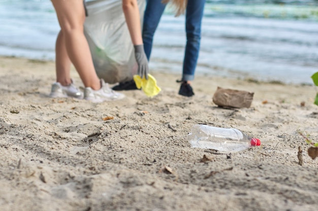 Foto grupo de adolescentes en la orilla del río recogiendo basura plástica en bolsas. concepto de protección del medio ambiente, juventud, voluntariado, caridad y ecología
