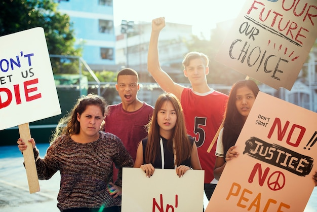 Grupo de adolescentes que protesta la demostración que sostiene el concepto pacifista de la paz de los carteles de la cartelera