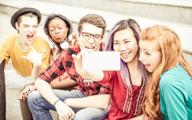 Grupo de adolescentes sentados en las escaleras y tomando selfie