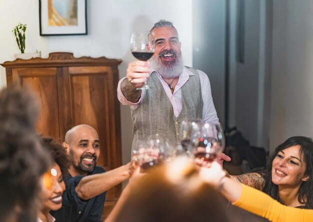 Foto grupo de adultos haciendo un brindis de celebración sentados en una mesa durante la cena