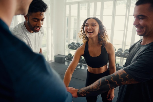 Un grupo de adultos jóvenes multirraciales felices en ropa deportiva celebrando en el gimnasio
