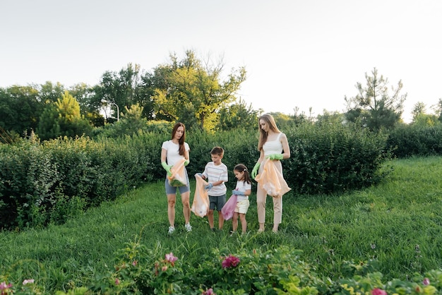 Un grupo de adultos y niños juntos al atardecer se dedica a la recolección de basura en el parque Reciclaje de residuos de cuidado ambiental Clasificación de basura