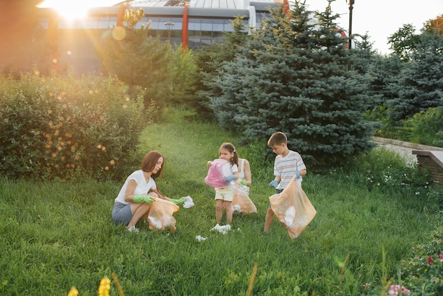 Un grupo de adultos y niños juntos al atardecer se dedica a la recolección de basura en el parque Reciclaje de residuos de cuidado ambiental Clasificación de basura