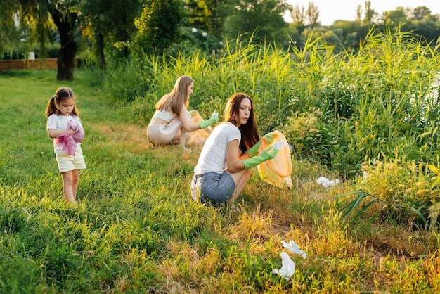 Un grupo de adultos y niños juntos al atardecer se dedica a la recolección de basura en el parque Reciclaje de residuos de cuidado ambiental Clasificación de basura