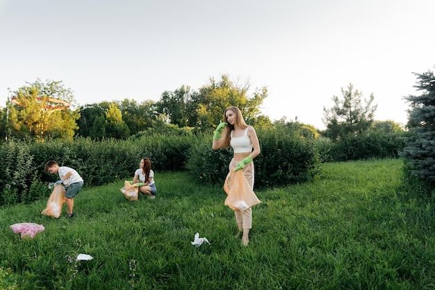 Un grupo de adultos y niños juntos al atardecer se dedica a la recolección de basura en el parque Reciclaje de residuos de cuidado ambiental Clasificación de basura