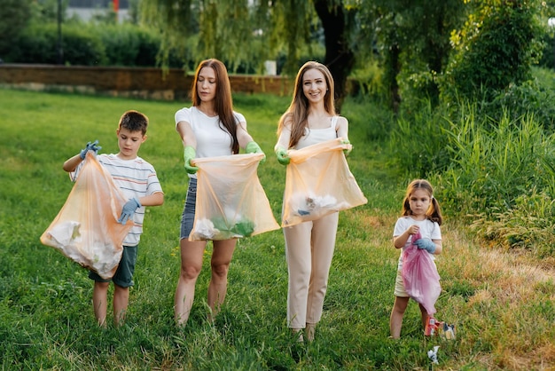 Un grupo de adultos y niños juntos al atardecer se dedica a la recolección de basura en el parque Reciclaje de residuos de cuidado ambiental Clasificación de basura