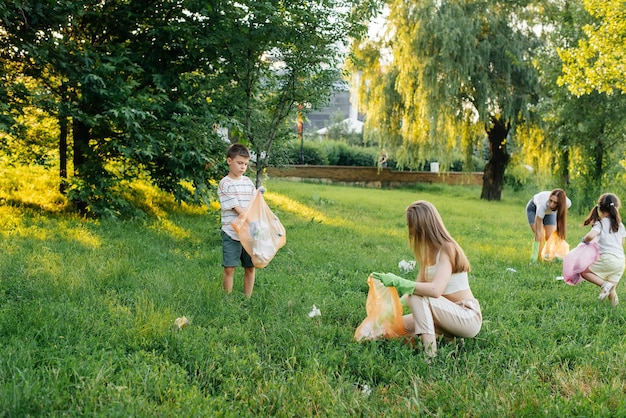 Un grupo de adultos y niños juntos al atardecer se dedica a la recolección de basura en el parque Reciclaje de residuos de cuidado ambiental Clasificación de basura