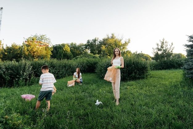 Un grupo de adultos y niños juntos al atardecer se dedica a la recolección de basura en el parque Reciclaje de residuos de cuidado ambiental Clasificación de basura