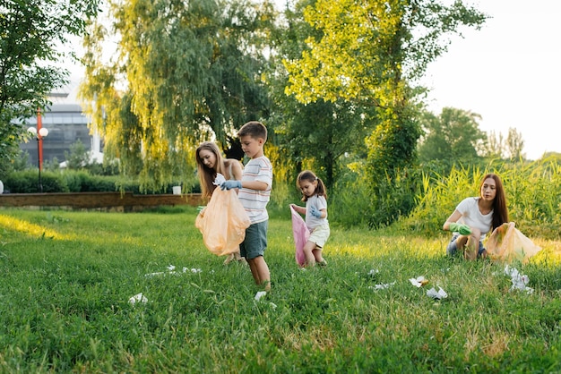 Un grupo de adultos y niños juntos al atardecer se dedica a la recolección de basura en el parque Reciclaje de residuos de cuidado ambiental Clasificación de basura