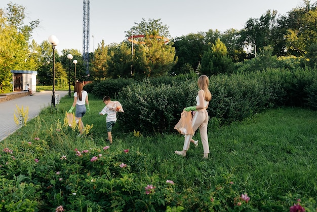 Un grupo de adultos y niños juntos al atardecer se dedica a la recolección de basura en el parque Reciclaje de residuos de cuidado ambiental Clasificación de basura