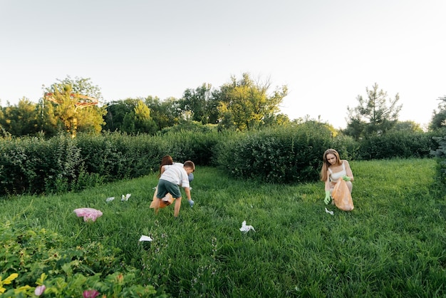 Un grupo de adultos y niños juntos al atardecer se dedica a la recolección de basura en el parque Reciclaje de residuos de cuidado ambiental Clasificación de basura