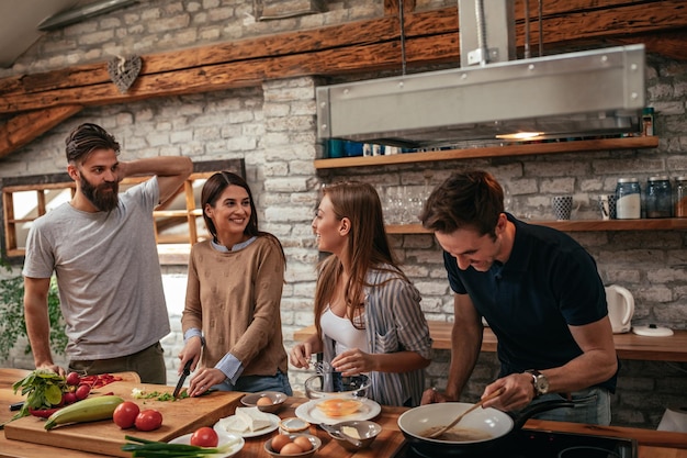 Grupo alegre de amigos fazendo uma refeição deliciosa em casa