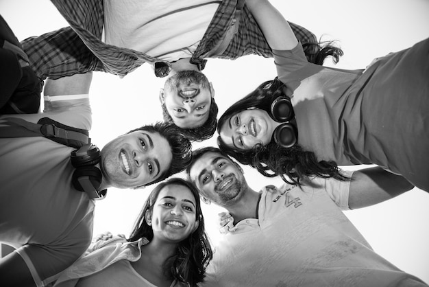 Grupo alegre de jovens indianos asiáticos de estudantes universitários formando um círculo, olhando para a câmera.