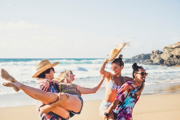 Grupo alegre de meninos e meninas se divertem juntos na praia durante as férias de verão