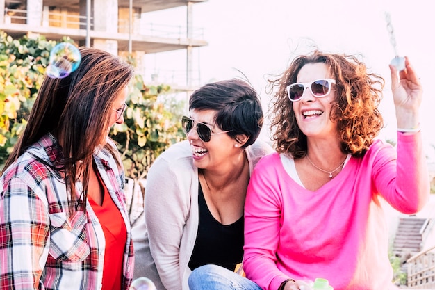 Grupo alegre e feliz de amigos yong mulher se divertindo juntos em amizade, brincando e rindo com bolhas de sabão - rindo muito em atividades de lazer ao ar livre para mulheres brancas