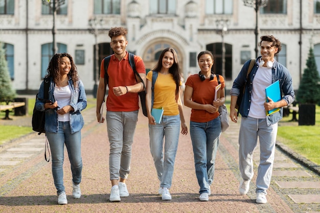 Un grupo de alegres estudiantes universitarios saliendo juntos del campus.