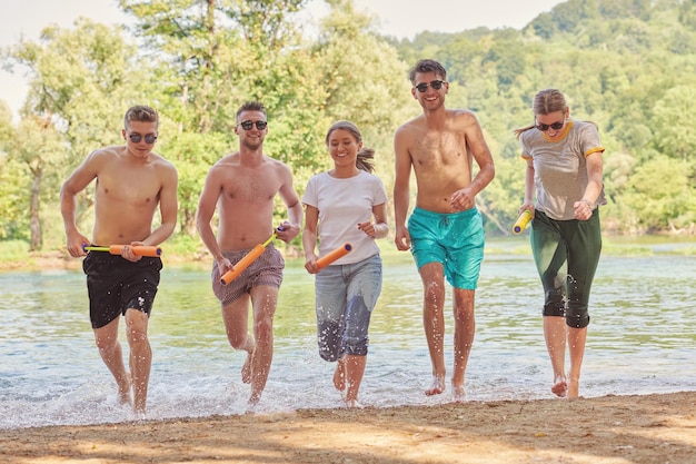 Grupo de alegría de verano de amigos felices divirtiéndose mientras corren y chapotean en el río