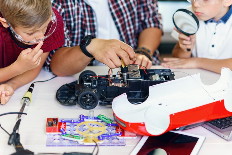 Foto grupo de alumnos varones jóvenes con científico asiático reparar modelo de coche controlado por radio.