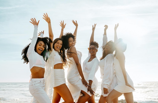 Grupo de amigas felices animando con los brazos levantados mientras celebran la despedida de soltera en el