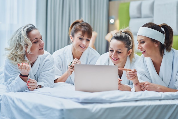 Grupo de amigas en la fiesta del spa del hotel con laptop