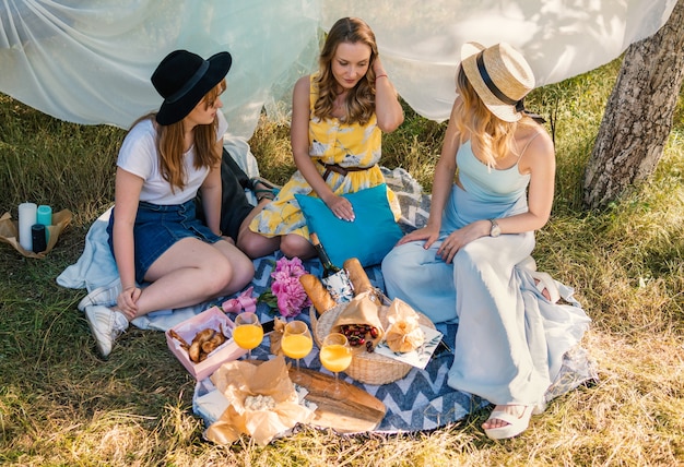 Grupo de amigas haciendo picnic al aire libre. Se sientan en el césped