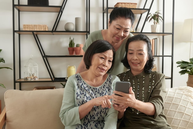 Grupo de amigas mayores discutiendo y eligiendo fotos para cargar en las redes sociales