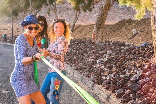 Grupo de amigas con ropa colorida y alegre estilo casual disfrutan juntas jugando con un cable feliz actividad de ocio al aire libre y sonríen disfrutan el estilo de vida y se mantienen jóvenes