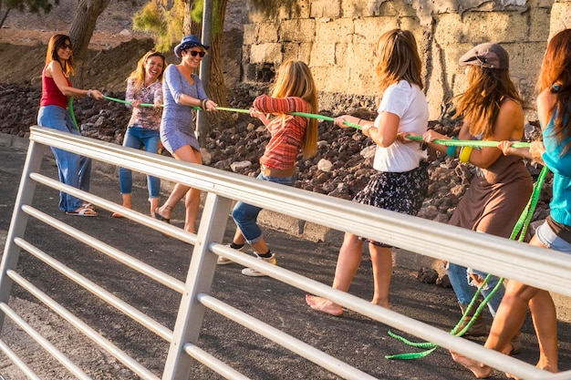 Grupo de amigas con ropa colorida y alegre estilo casual disfrutan juntas jugando con un cable feliz actividad de ocio al aire libre y sonríen disfrutan el estilo de vida y se mantienen jóvenes