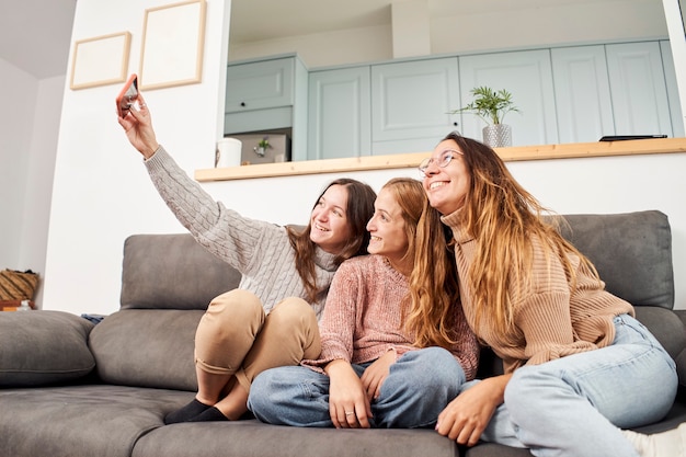 Grupo de amigas en el sofá en casa tomando un selfie