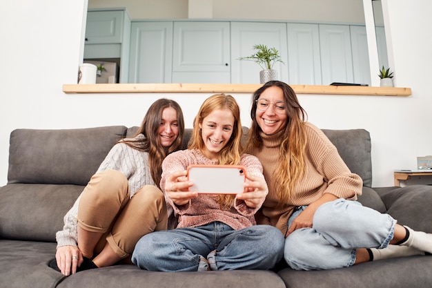 Grupo de amigas en el sofá en casa tomando un selfie