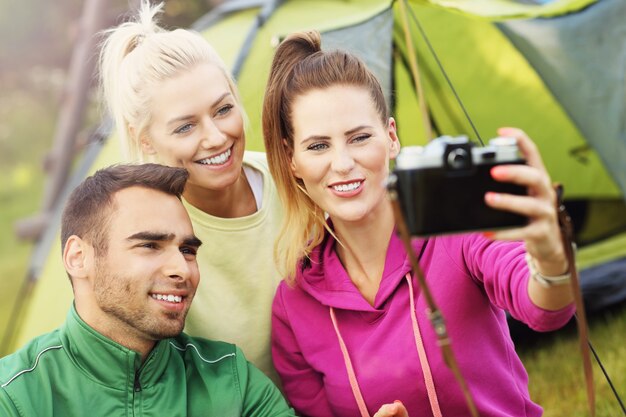 Grupo de amigos acampando en el bosque y tomando selfie