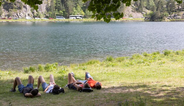 Foto grupo de amigos acostados pasando la tarde en las orillas de un lago en un día soleado