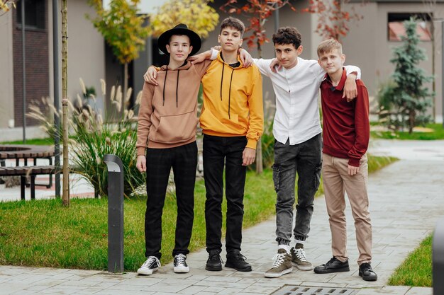 Foto grupo de amigos adolescentes sonrientes y felices con ropa casual pasando tiempo juntos posando y hablando entre sí cerca del edificio de la universidad en un día de otoño