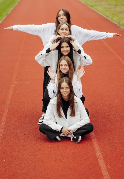 Un grupo de amigos adolescentes sonrientes y felices vestidos con ropa casual pasan tiempo juntos posando y divirtiéndose en el recinto de una institución educativa en un día de otoño