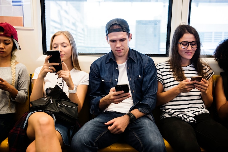 Foto grupo de amigos adultos jóvenes que usan teléfonos inteligentes en el metro