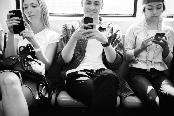 Foto grupo de amigos adultos jóvenes que usan teléfonos inteligentes en el metro