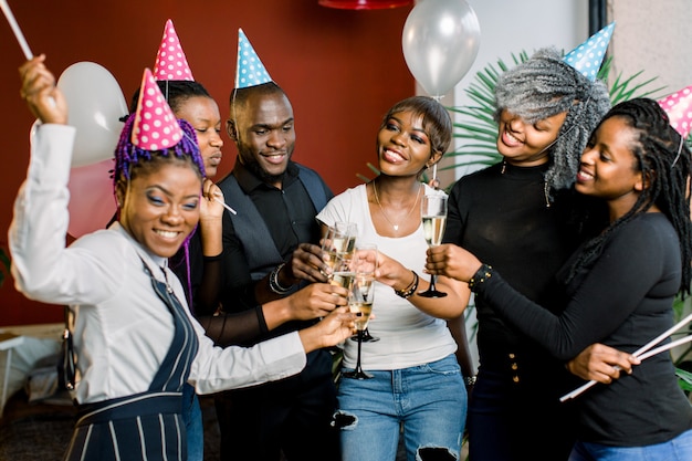 Grupo de amigos africanos felices bebiendo champán y celebrando la fiesta de cumpleaños